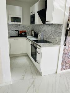 a white kitchen with white cabinets and appliances at SUITE-XXI City View Hotelturm Augsburg in Augsburg