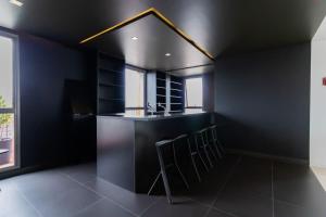 a black kitchen with a bar with stools at Studios Novíssimos com Piscina no Rooftop e vista para o Allianz Parque in Sao Paulo