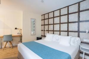 1 dormitorio con 1 cama blanca grande y escritorio en Madeinterranea Suites en Málaga