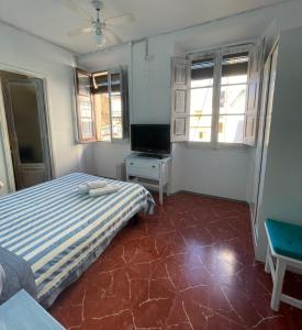 a bedroom with a bed and a tv and windows at P&R hostals Can Tort in Tossa de Mar