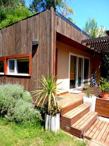 ein Haus mit einer Holzterrasse mit einer Pflanze davor in der Unterkunft La Escondida in Valeria del Mar