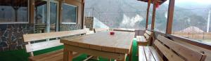 a wooden table on a balcony with a view of a mountain at Casa Găleată in Nehoiu