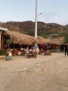 a building with a straw roof and tables and chairs at Casa Toboro in Taganga
