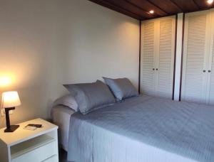 een slaapkamer met een bed en een tafel met een lamp bij Búzius na Praia da Ferradura Frente mar in Búzios