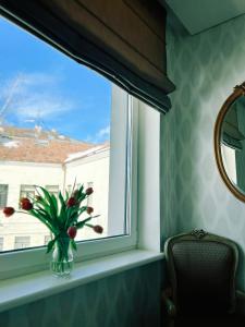 ein Fenster mit einer Vase aus Blumen auf einem Fensterbrett in der Unterkunft Castle Apartaments host Kaunas with free parking in Kaunas