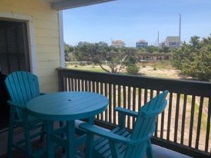 - deux chaises bleues et une table sur un balcon dans l'établissement SunSet Terrace, Avon NC, à Avon