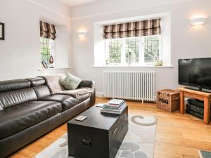 a living room with a leather couch and a flat screen tv at Connie's Cottage in Ambleside