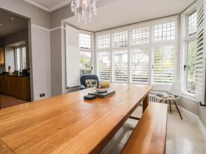 a dining room with a wooden table and windows at Connie's Cottage in Ambleside