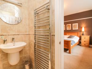 a bathroom with a sink and a mirror and a bed at Connie's Cottage in Ambleside +30 photos