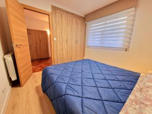 a bedroom with a blue bed and a window at Chabós Plaza España - Charming Flats in Vigo