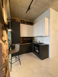 une cuisine avec des armoires en noir et blanc et une chaise dans l'établissement Dark Apartment, à Erevan