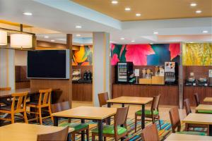 Fairfield Inn & Suites by Marriott Bridgewater Branchburg/Somerville في Branchburg Park: مطعم به طاولات وكراسي وتلفزيون