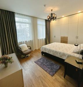 a bedroom with a bed and a chair and a window at Castle Apartaments host Kaunas with free parking in Kaunas