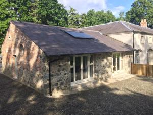 an old stone building with solar panels on the roof at The Mews -- Luxury Stay at Bellingham Estate in Castlebellingham