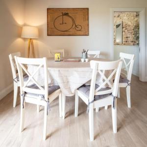 a dining room table with four chairs and a clock on the wall at The Mews -- Luxury Stay at Bellingham Estate in Castlebellingham