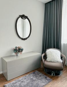 a living room with a chair and a table and a mirror at Castle Apartaments host Kaunas with free parking in Kaunas