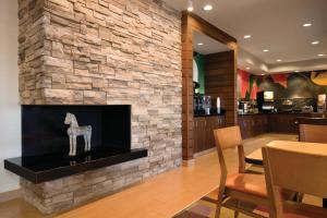 a lobby with a stone fireplace with a table and chairs at Fairfield Inn Muncie in Muncie