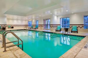 una piscina en una habitación de hotel con sillas azules en Residence Inn Charlotte SouthPark, en Charlotte