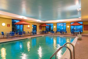 a pool in a hotel with tables and chairs at TownePlace Suites Fort Wayne North in Fort Wayne