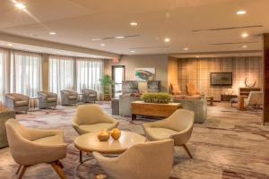 格林斯伯勒的住宿－格林斯博羅機場萬怡酒店，大堂设有椅子、桌子和电视。