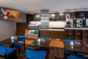 a restaurant with tables and blue chairs and a kitchen at Courtyard Cincinnati Covington in Covington