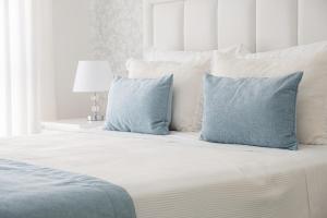 een slaapkamer met een bed met blauwe kussens bij Olhos d'Água - Penthouse in Nazaré