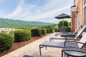 une terrasse avec des chaises, des tables et un parasol dans l'établissement Fairfield Inn & Suites Chattanooga I-24/Lookout Mountain, à Chattanooga