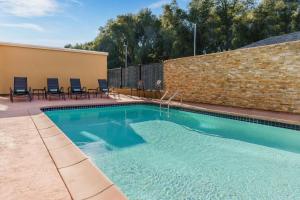 uma piscina com cadeiras e uma parede de tijolos em Fairfield Inn & Suites by Marriott Oakhurst Yosemite em Oakhurst