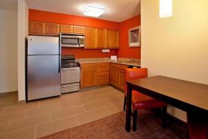 La cuisine est équipée d'un réfrigérateur en acier inoxydable et de placards en bois. dans l'établissement Residence Inn Fort Wayne Southwest, à Fort Wayne