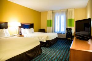a hotel room with two beds and a flat screen tv at Fairfield Inn & Suites Fredericksburg in Fredericksburg