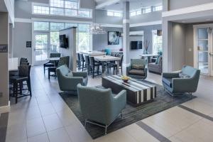 a lobby with chairs and a table and a dining room at Residence Inn Milford in Milford
