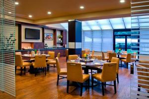 a restaurant with tables and chairs and a television at Trumbull Marriott Shelton in Trumbull