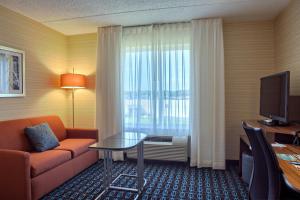 une chambre d'hôtel avec un canapé, une table et une fenêtre dans l'établissement Fairfield Inn Harrisburg Hershey, à Harrisburg