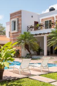 une villa avec une piscine et deux chaises blanches dans l'établissement Casa privada con alberca grande, à Chetumal