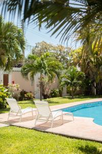 - un groupe de chaises assises à côté de la piscine dans l'établissement Casa privada con alberca grande, à Chetumal