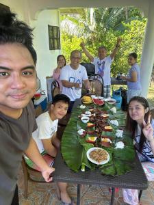 a group of people sitting around a table with food at Riverside Transient House/Balingasay-Patar Beach in Balingasay