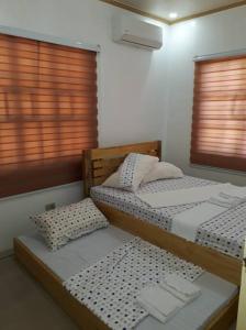 two twin beds in a room with two windows at Riverside Transient House/Balingasay-Patar Beach in Balingasay