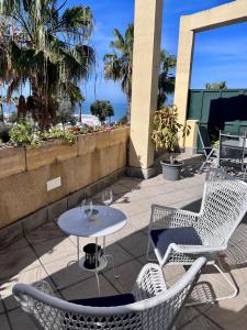 patio z 2 krzesłami i stołem z kieliszkami do wina w obiekcie GATU Villa Atardecer en la playa de las Redes " Preferente mayores de 21 años y familias " w mieście El Puerto de Santa María