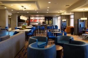 a restaurant with blue chairs and tables and a bar at Courtyard by Marriott Bloomington in Bloomington