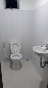 a white bathroom with a toilet and a sink at Riverside Transient House/Balingasay-Patar Beach in Balingasay