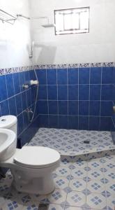 a bathroom with a toilet and a blue tiled floor at Riverside Transient House/Balingasay-Patar Beach in Balingasay