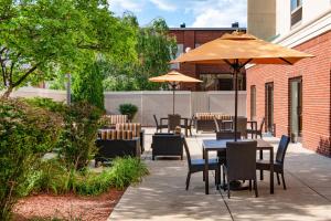 un patio con mesas, sillas y una sombrilla en Courtyard by Marriott Bloomington, en Bloomington