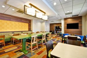 a dining room with tables and chairs and a flat screen tv at Fairfield Inn & Suites by Marriott Atlanta Vinings/Galleria in Atlanta
