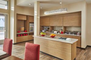 a kitchen with wooden cabinets and a counter with red chairs at TownePlace Suites by Marriott Columbus North - OSU in Columbus