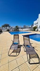 2 sillas sentadas junto a una piscina en Santos Apartment, en Santa Luzia