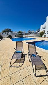 two chairs sitting next to a swimming pool at Santos Apartment in Santa Luzia