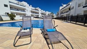- deux chaises de plage installées à côté de la piscine dans l'établissement Santos Apartment, à Santa Luzia