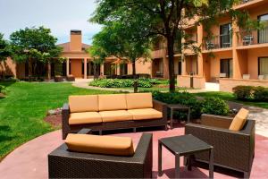 a patio with a couch and tables and a building at Courtyard Detroit Metro Airport Romulus in Romulus