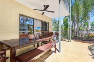 a patio with a wooden bench and a ceiling fan at Casa De Playa - Beach Townhouse in Holloways Beach