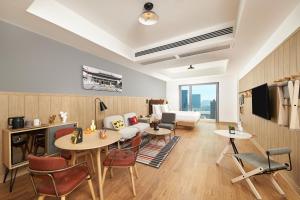 Moxy Nanjing Jiangning في نانجينغ: غرفة معيشة مع طاولات وكراسي وأريكة